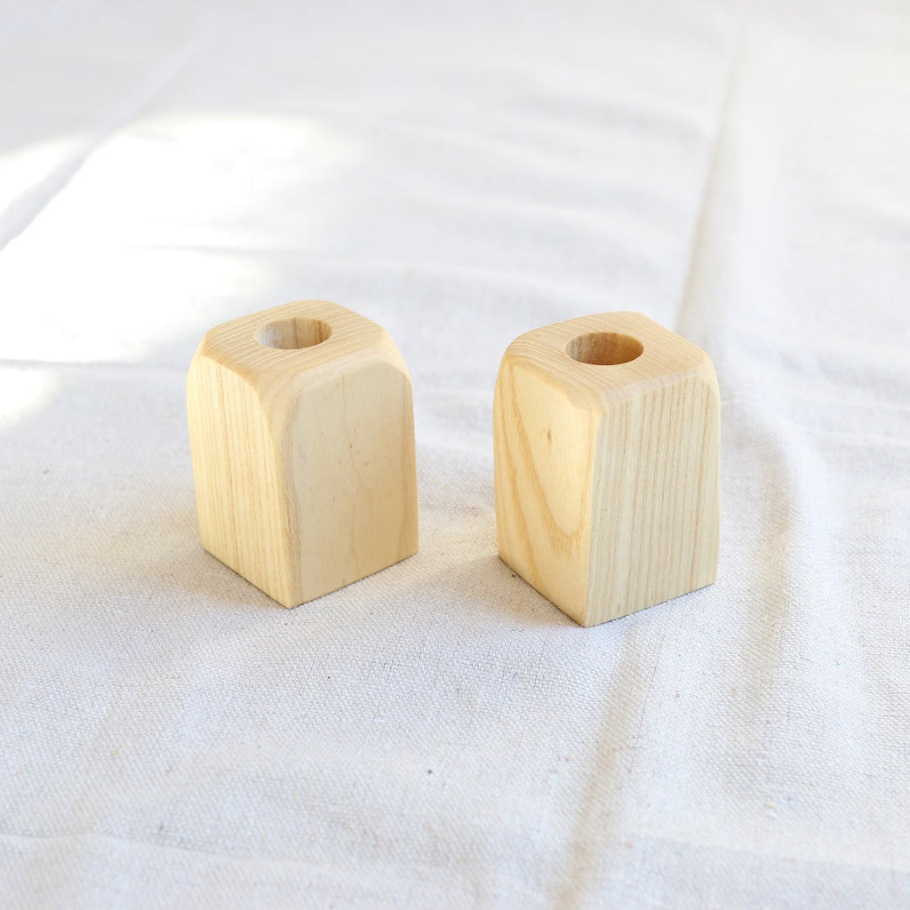Two wooden candle holders on a white fabric background