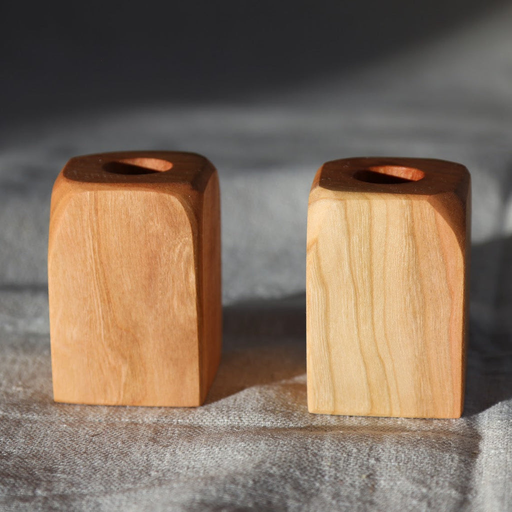 Two wooden candle holders on a textured fabric background