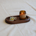 Wooden tray with a candle and small card on a white fabric background